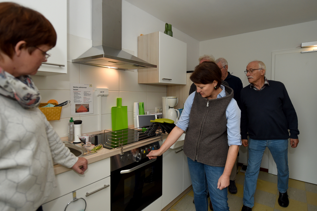 Frau zeigt einer Gruppe Herdabschaltung